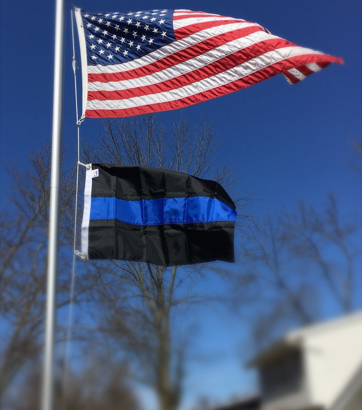 The American flag and the Thin Blue Line flag flying on a flagpole
